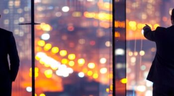 Professionals looking out the top of an office building pointing at the city lights